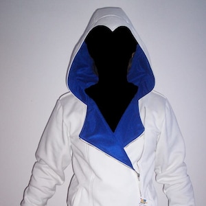 Può includere: Felpa con cappuccio bianca con fodera blu sul cappuccio. La cerniera è sul lato e la felpa ha una tasca sul davanti.