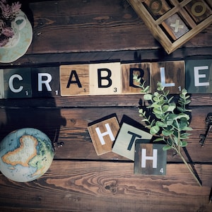 May include: Wooden Scrabble tiles spelling out the word "SCRABBLE" with a green plant and a globe in the background.