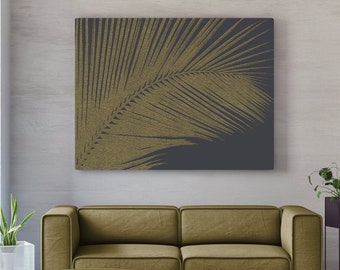 May include: A mustard yellow sofa with a matching ottoman in front of a wall with a gold leaf palm tree print on a dark gray background.