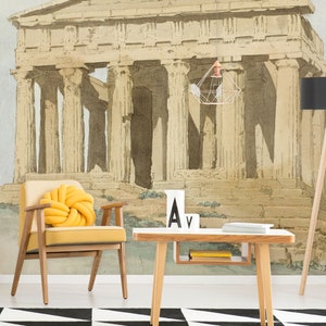 Peut inclure: Un fauteuil jaune avec un coussin jaune noué est placé devant une table basse blanche avec des livres sur l'étagère. Le mur derrière les meubles présente une peinture à l'aquarelle d'un temple grec antique.
