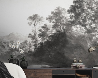 May include: A white armchair with a black and white throw blanket sits in front of a dark wood media console with black shelves. The console is filled with books and magazines. The wall behind the furniture is covered in a black and white landscape mural.