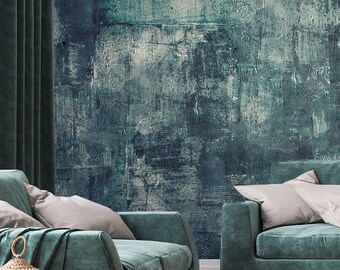 Könnte beinhalten: Ein Wohnzimmer-Interieur mit einem blaugrünen Sofa, zwei passenden Sesseln und einem Couchtisch. Die Wand hinter den Möbeln ist in einem dunklen Blaugrün mit einem strukturierten, abstrakten Muster gestrichen. Der Raum ist mit einer Vase mit Trockenblumen, einer Wolldecke und einer Lampe auf einem Beistelltisch dekoriert.