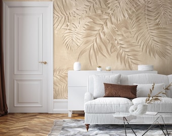 May include: A white sofa with brown throw pillows sits in a living room with a beige wall featuring a large-scale palm leaf print wallpaper.