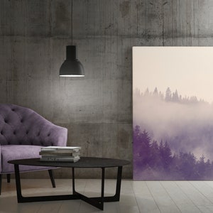 Puede incluir: Un sillón de terciopelo morado con capitoné de botones se encuentra frente a una mesa de café negra con una pila de libros. Una gran impresión en lienzo de una escena de bosque brumoso cuelga en la pared detrás de los muebles.