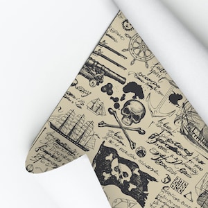 May include: A beige and black patterned wallpaper roll with a pirate theme. The pattern includes skulls, crossbones, ships, anchors, cannons, and other nautical elements. The wallpaper is rolled up and partially unrolled, revealing the pattern.