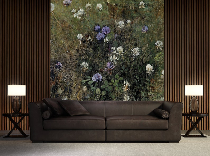 May include: A dark brown leather sofa with two pillows in front of a wall with a floral print. The print features white and purple flowers on a green background.
