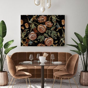 Puede incluir: Una escena de comedor con una gran obra de arte bordada con flores. La obra presenta rosas en tonos marrón, naranja y verde sobre un fondo negro. La habitación incluye un banco de terciopelo marrón, dos sillas, una mesa redonda y plantas.