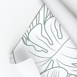 Puede incluir: Un rollo de papel tapiz blanco con un dibujo de hojas tropicales en l&iacute;nea verde. El texto "My Wall Store" es visible en la parte superior de la imagen.