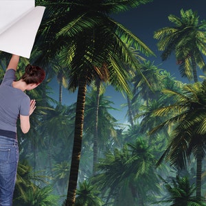 May include: A person is applying a tropical palm tree wallpaper to a wall. The wallpaper features a lush green jungle scene with palm trees and a blue sky.