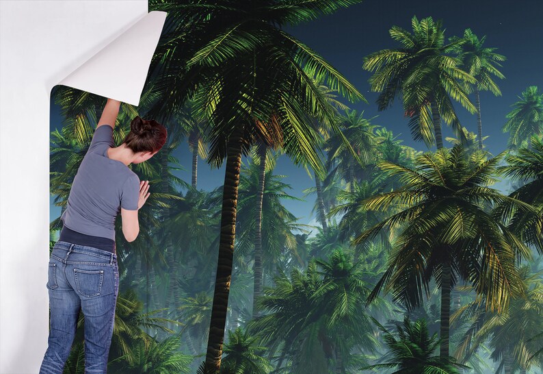 May include: A person is applying a tropical palm tree wallpaper to a wall. The wallpaper features a lush green jungle scene with palm trees and a blue sky.