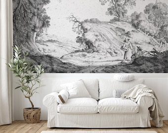 May include: A white sofa with a white throw blanket and a black and white patterned pillow. The sofa is in front of a wall with a black and white print of a landscape with a figure in the foreground.