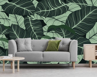 Könnte beinhalten: Ein graues Sofa mit zwei Kissen steht vor einer Wand mit einer grünen und weißen Tapete mit tropischem Blattmotiv.