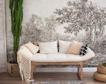 May include: A white couch with a wooden frame and white cushions sits in front of a wall with a black and white nature-themed wallpaper. The couch has a throw blanket draped over the armrest.