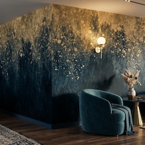 May include: A room featuring a wall with a dark blue to gold gradient paint effect, decorated with scattered gold speckles. The space includes two dark blue curved sofas, a matching armchair with a throw, and a small table with a dried floral arrangement.