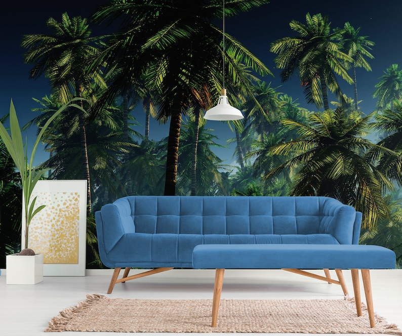 May include: A blue velvet sofa and matching ottoman in front of a tropical palm tree mural. The mural features a dark blue sky with green palm trees.