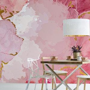May include: A dining room with a pink and gold abstract wallpaper, a white pendant light, a wooden table with four chairs, and a potted plant.