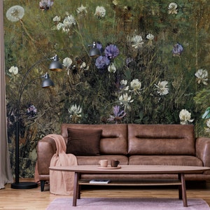 May include: A brown leather sofa with a brown throw blanket and a wooden coffee table in front of it. The wall behind the sofa is covered in a floral wallpaper with a green, brown, and white color scheme.