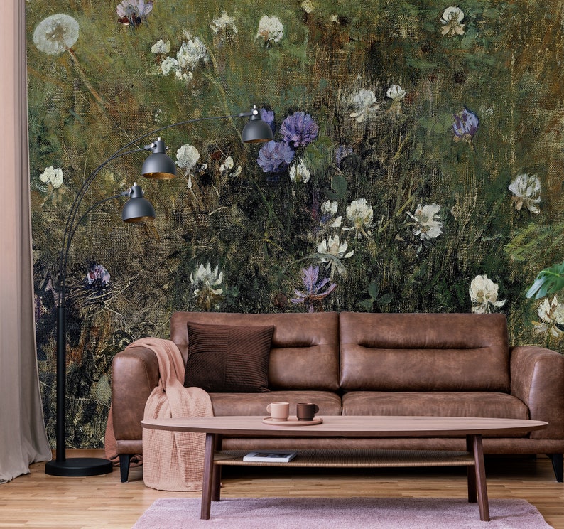 May include: A brown leather sofa with a brown throw blanket and a wooden coffee table in front of it. The wall behind the sofa is covered in a floral wallpaper with a green, brown, and white color scheme.