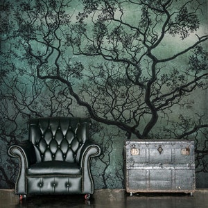 May include: A black leather armchair with a tufted back and seat sits in front of a wall with a large, abstract tree branch design in shades of green and gray. A vintage metal trunk with a distressed finish sits on the floor next to the chair.