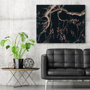 Puede incluir: Una fotografía en blanco y negro de una rama de árbol con flores rosas colgando de ella. La imagen está enmarcada y colgada en una pared sobre un sofá de cuero negro.