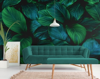 Peut inclure: Un canapé vert turquoise avec un ottoman assorti devant un mur avec un imprimé de feuilles tropicales à grande échelle. Les feuilles sont de couleur vert foncé et turquoise.