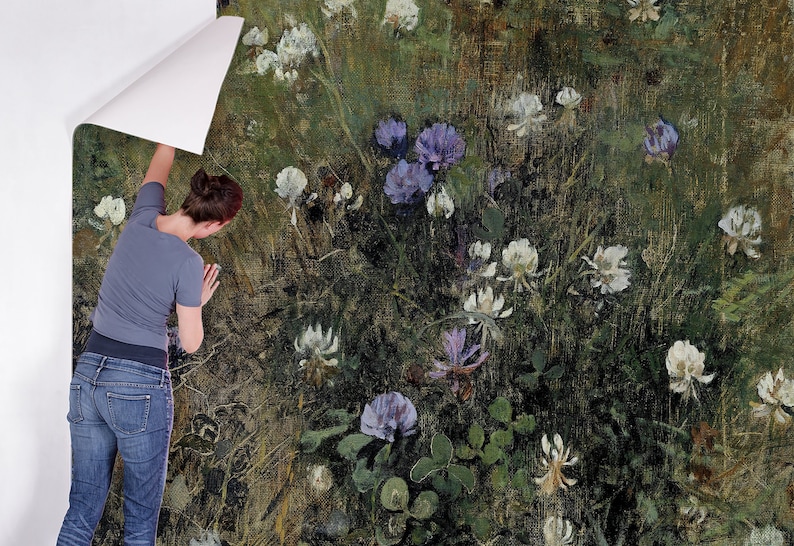 May include: A person is applying a floral wallpaper with a green background and white and purple flowers. The wallpaper has a textured, painterly look.