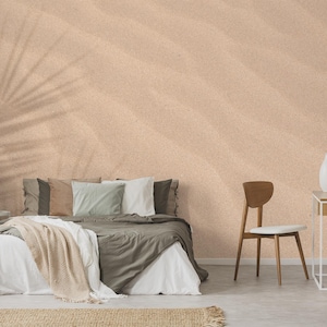 Puede incluir: Una cama blanca con una manta de color marrón claro y algunas almohadas. La cama está en una habitación con una pared de color marrón claro y una silla de madera. La pared tiene un patrón sutil de líneas marrones claras.