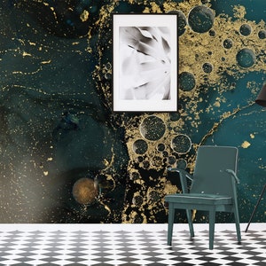 May include: A teal and gold abstract wall mural with a black and white photo in a black frame hanging on the wall. A teal chair sits in front of the wall.