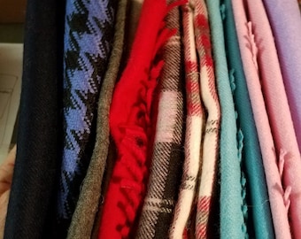 May include: A collection of folded scarves in various colors and patterns, including black, blue, red, white, pink, and teal.