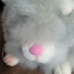 May include: A plush toy hamster with light blue fur, white paws, and a pink nose.