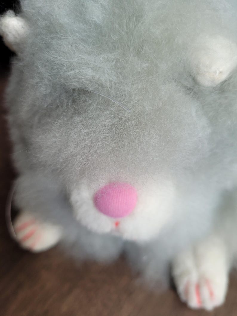 May include: A plush toy hamster with light blue fur, white paws, and a pink nose.