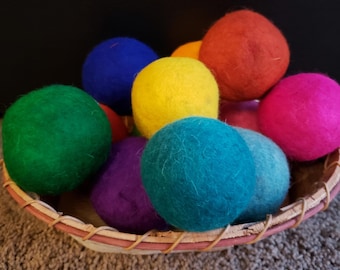 May include: A basket filled with colorful wool dryer balls in shades of green, blue, yellow, red, pink, and purple. The balls are made of felted wool and are used to soften laundry and reduce drying time.
