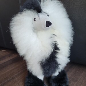 K&ouml;nnte beinhalten: Ein schwarzes und wei&szlig;es Pl&uuml;schspielzeug-Pudel mit einem flauschigen wei&szlig;en K&ouml;rper und schwarzen Beinen und Kopf. Das Spielzeug hat ein graues Gesicht mit schwarzen Augen und einer schwarzen Nase.