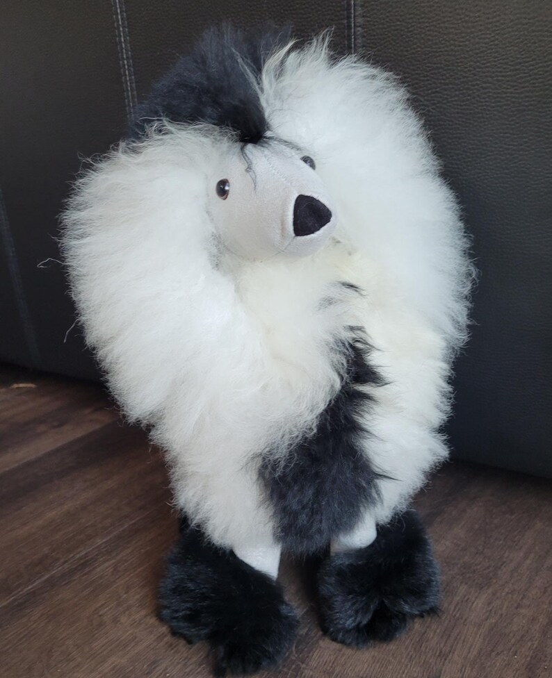 K&ouml;nnte beinhalten: Ein schwarzes und wei&szlig;es Pl&uuml;schspielzeug-Pudel mit einem flauschigen wei&szlig;en K&ouml;rper und schwarzen Beinen und Kopf. Das Spielzeug hat ein graues Gesicht mit schwarzen Augen und einer schwarzen Nase.