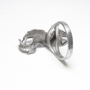 Puede incluir: Anillo plateado con un dise&ntilde;o detallado de rinoceronte. El anillo tiene un acabado texturizado y una banda ancha. La cabeza y el cuerno del rinoceronte se muestran de forma prominente.