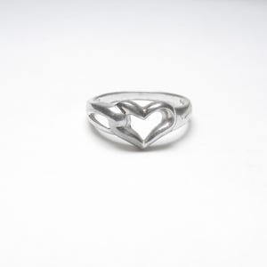 May include: A silver ring with a heart-shaped cutout design.