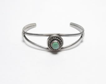 May include: A silver bracelet with a turquoise stone set in a circular design.