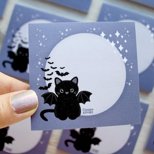 May include: A square, light purple sticker featuring a black cat with bat wings, a full moon, and bats flying across the sky. The sticker has a white moon and star accents. The text "Chester & Pearl" is at the bottom.