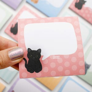 May include: A pink sticky note with a white speech bubble and a black cat illustration. The note has a polka dot pattern and the text "Chester & Pearl". Other notes with cat illustrations are in the background.