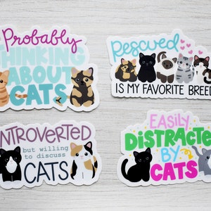 May include: Four cat-themed stickers with colorful text and illustrations. The stickers feature phrases like "Probably Thinking About Cats", "Rescued is My Favorite Breed", "Introverted but Willing to Discuss Cats", and "Easily Distracted by Cats".