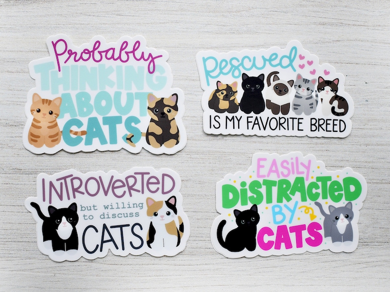 May include: Four cat-themed stickers with colorful text and illustrations. The stickers feature phrases like "Probably Thinking About Cats", "Rescued is My Favorite Breed", "Introverted but Willing to Discuss Cats", and "Easily Distracted by Cats".