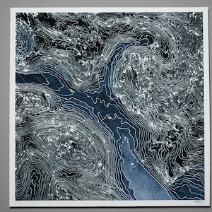 Könnte beinhalten: Abstrakter Kunstdruck mit einem topografischen Kartendesign. Das Kunstwerk zeigt eine dunkelblaue flussartige Form vor einem schwarzen Hintergrund mit weißen Konturlinien. Der Druck befindet sich auf einem weißen quadratischen Papier.