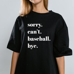 May include: Black t-shirt with white text that reads "sorry. can't. baseball. bye."