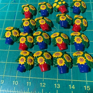 May include: A collection of 15 miniature potted sunflowers with green leaves and yellow flowers. The pots are red, blue, and green.