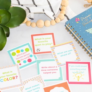 May include: Colorful cards with questions to spark conversation.  The cards have a variety of colors and patterns.  The text on the cards includes questions like "What is your favorite color?" and "Who is your favorite person in the world?"