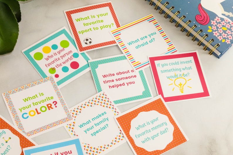 May include: A set of colorful cards with prompts for conversation starters. The cards feature a variety of designs and colors, including red, orange, yellow, green, blue, and white. The text on the cards includes questions such as "What is your favorite color?" and "Who is your favorite person in the world?"