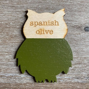 May include: Wooden owl-shaped paint chip with the text "spanish olive" and a painted sample of the color.