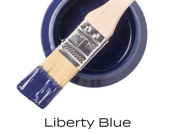 Può includere: Un piccolo barattolo di vernice blu con un pennello sopra. Il barattolo è etichettato "Fusion Mineral Paint" e il colore è "Liberty Blue".