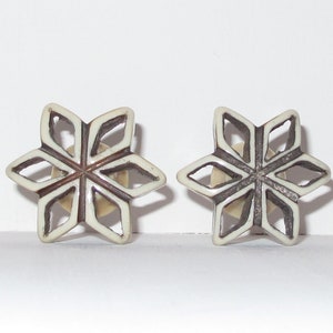 May include: A pair of snowflake-shaped earrings with a white and brown design.