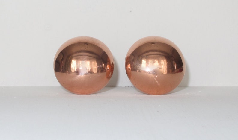 May include: Two shiny copper spheres, each with a smooth, reflective surface.